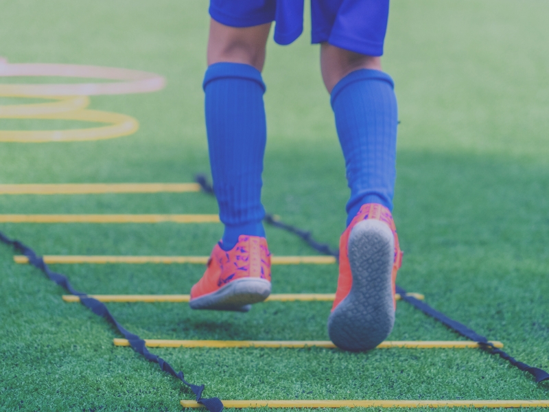 Agility ladder training instruments used by a soccer player in blue gear for speed improvement.