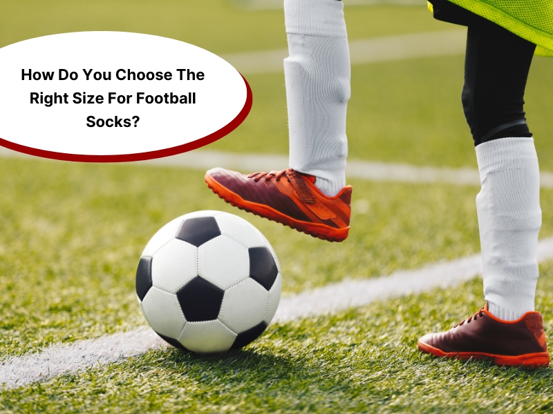 Player in orange cleats and white socks standing next to a football, highlighting the football sock size guide.